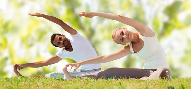 Two people doing yoga in a field.